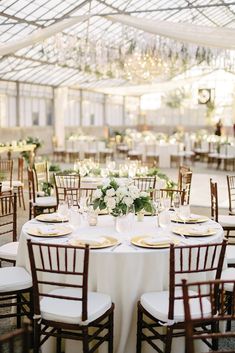 the tables are set with white linens and gold place settings for an elegant reception