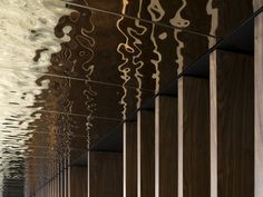 a long hallway with wooden walls and mirrors on the wall, reflecting water in it