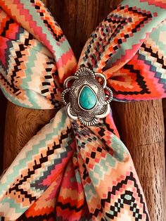 Wild Rag Western concho slide. This one is Aztec  pattern with silver in scalloped shape with pear shaped turquoise stone at center. lThis is a simple slide and will go with all your scarves.  This is smaller Slide measuring  1-1/4 and 1.5" across. Has custom backing to hold scarf made of silver solder and stainless. Please check out our other items as some are complimentary to this item. If you buy 2 or more items you will get 15% off! Spend $50 and get 20% off. We can ship multiple items for one normal shipping cost. We take custom order requests as well. Scarf Slide, Floral Bandana, Wild Rag, Southwestern Design, Western Design, Cowboy Cowgirl, Aztec Pattern, Chain Belt, Cowboy And Cowgirl