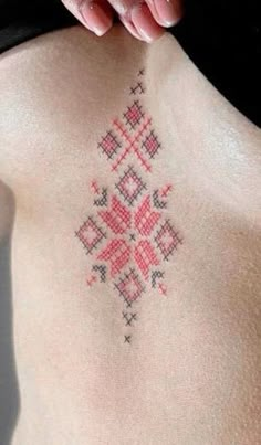 a woman's chest with a cross stitched design on the back of her stomach