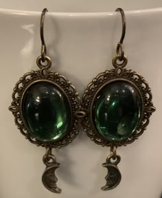 "Beautiful, understated and oh so Witchy. These earrings feature gorgeous Czech glass tourmaline cabochons set in an antique bronze Victorian style setting with tiny crescent moons dangling below. Bronze hypoallergenic niobium ear wires complete the look. Length: 2.25\" (including ear wire) Width: .75\" All Moon Grove Designs jewelry comes beautifully gift boxed and ready for giving to yourself or someone special." Dream Jewelry Earrings, Witchy Glasses, Bronze And Gold Jewelry, Vintage Crescent Moon Charm Earrings, Strange Jewelry, Vintage Moon-shaped Metal Earrings, Witchy Trinkets, Nickel-free Bronze Crescent Jewelry, Whimsigothic Jewelry