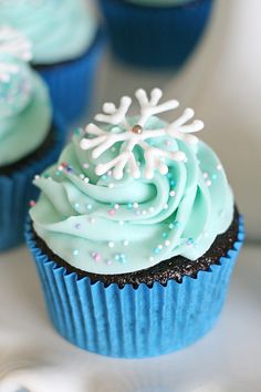 blue cupcakes with frosting and sprinkles on white tablecloth