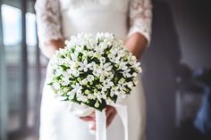 a bride holding a bouquet of white flowers