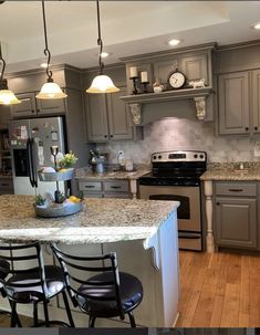 a kitchen with gray cabinets and marble counter tops