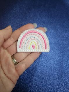 a hand holding a small felt brooch with a rainbow on the inside of it