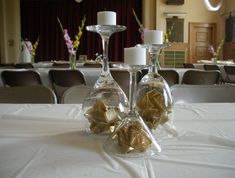 two wine glasses with gold foil wrapped in paper are sitting on a table next to candles