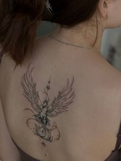 the back of a woman's shoulder with an angel tattoo on her upper arm