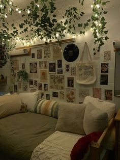 a living room filled with lots of pillows and plants hanging from the ceiling above it