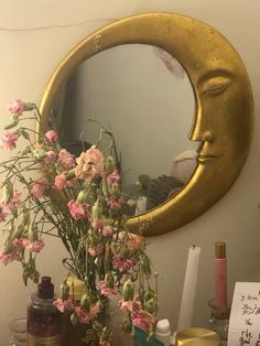 a vase filled with flowers sitting on top of a table next to a mirror and bottles