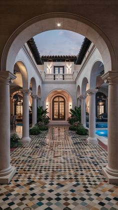 an archway leading to a swimming pool in a home with tiled flooring and columns