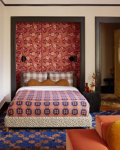 a bed sitting in the middle of a bedroom next to a wall with flowers on it