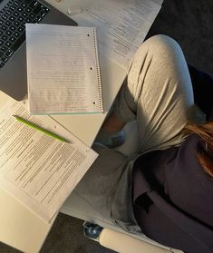 a woman sitting at a desk with her laptop and papers in front of her on the floor