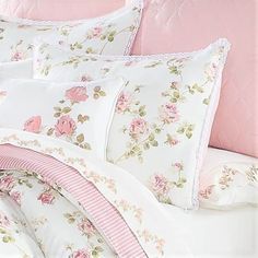 the comforter is made up with pink and white flowers on it's bed