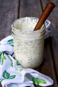 a jar filled with dressing sitting on top of a table next to a wooden spoon