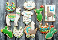 some decorated cookies are sitting on a wooden table with cactuses and llamas