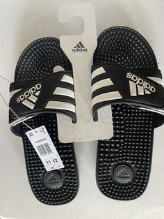 The adidas Adissage Sandals are a unisex slide-style sandal with a black and white striped pattern. They are available in US men's size 11 and women's size 12. The sandals feature a synthetic upper, lining, and insole, as well as a synthetic outsole. The product is part of the adissage product line and is made in Vietnam. Mens Shoes Sandals, Us Man, Sandals Black, Black Sandals, Shoes Sandals, Vietnam, Men's Shoes, Size 12, Shoe Accessories