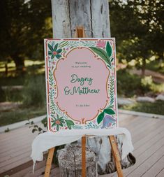 a sign that is on top of a wooden easel in front of a tree