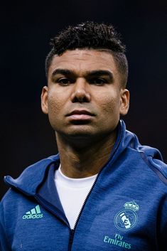 a close up of a person wearing a blue jacket and looking at the camera with an intense look on his face