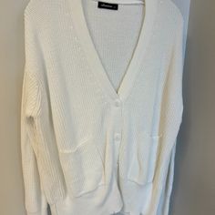 Never Worn. Oversized Fit. Long Sleeve White Sweater. Slightly Distressed Hemlines. Deep V Neckline, With Two Small Pockets And 4 White Buttons. Oversized White Ribbed Outerwear, Oversized Ribbed V-neck Outerwear, Oversized V-neck Ribbed Outerwear, Oversized Soft Knit White Cardigan, Oversized White Soft Knit Cardigan, White Textured Knit V-neck Cardigan, Oversized White Ribbed Sweater, Oversized White Cardigan For Layering, Trendy White Ribbed Outerwear