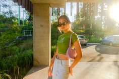 a young woman is standing on the sidewalk with her hand in her pocket and looking at the camera