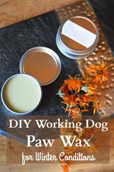 three tins filled with dog paw wax sitting on top of a wooden table next to flowers