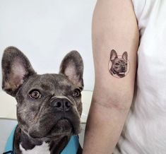 a small dog with a face tattoo on its arm next to a woman's arm