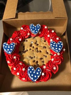 a cookie decorated with red, white and blue icing is in a cardboard box