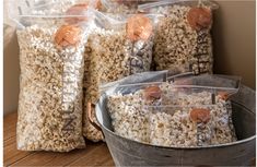 three bags of popcorn sitting on top of a wooden floor next to a bucket full of them