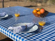 a blue and white checkered table cloth on a picnic table with oranges in the background