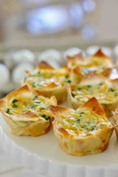 small quiche cups on a white plate with eggs in the backgroung