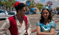 a man and woman dressed in costumes standing next to each other on the side of a road