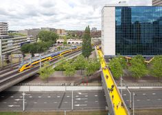 an aerial view of a train station with people walking on the platform and cars driving down the road