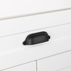 a black drawer handle on a white dresser