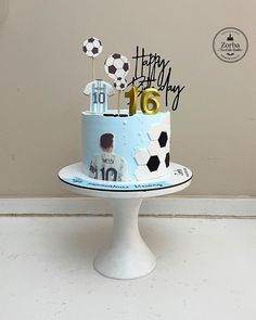 a birthday cake decorated with soccer balls and the number 16 on it is sitting on a pedestal