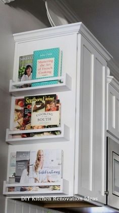 a kitchen with white cabinets and shelves filled with magazines on top of the cupboards