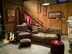 a living room filled with furniture next to a stair case and wooden paneled walls