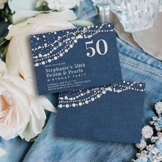 the wedding stationery is laid out on top of blue denims and white flowers