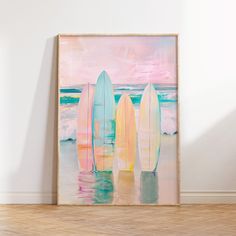 three surfboards are standing in the water with pink and blue skies behind them on a white wall