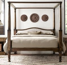 a four poster bed in a bedroom with white walls and wooden furniture, along with two chairs