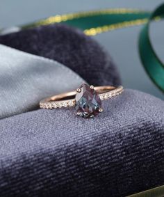 an engagement ring with a blue topazte surrounded by white and green diamonds on a gray cloth