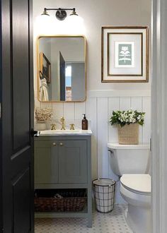 a white toilet sitting next to a bathroom sink under a mirror on top of a wall