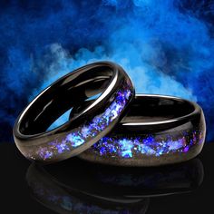 two black ceramic rings with blue and purple glitters on them, against a dark background