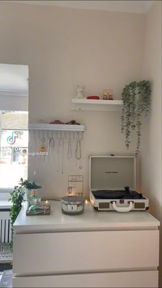 a living room with white furniture and plants on the shelf, including an old record player