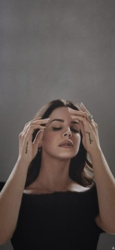 a woman holding her hands up to her face and looking at the sky with eyes closed