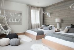 two beds in a room with white carpet and wooden walls, one bed is made up