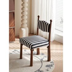 a black and white striped chair sitting in front of a tall vase on a rug