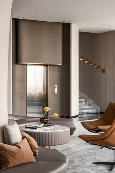 a living room with two chairs and a coffee table in front of a staircase leading up to the second floor