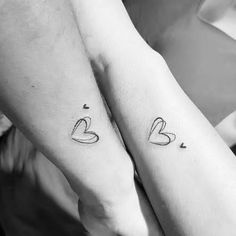 two people with tattoos on their arms holding each other's hands and one has a heart