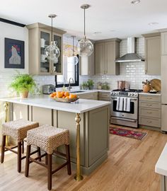 a kitchen with two stools in front of the counter and an island that has fruit on it