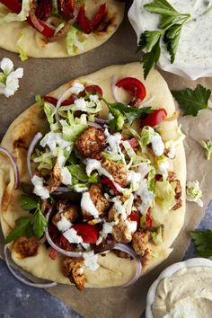 two pita breads with chicken, lettuce and tomato salad on top